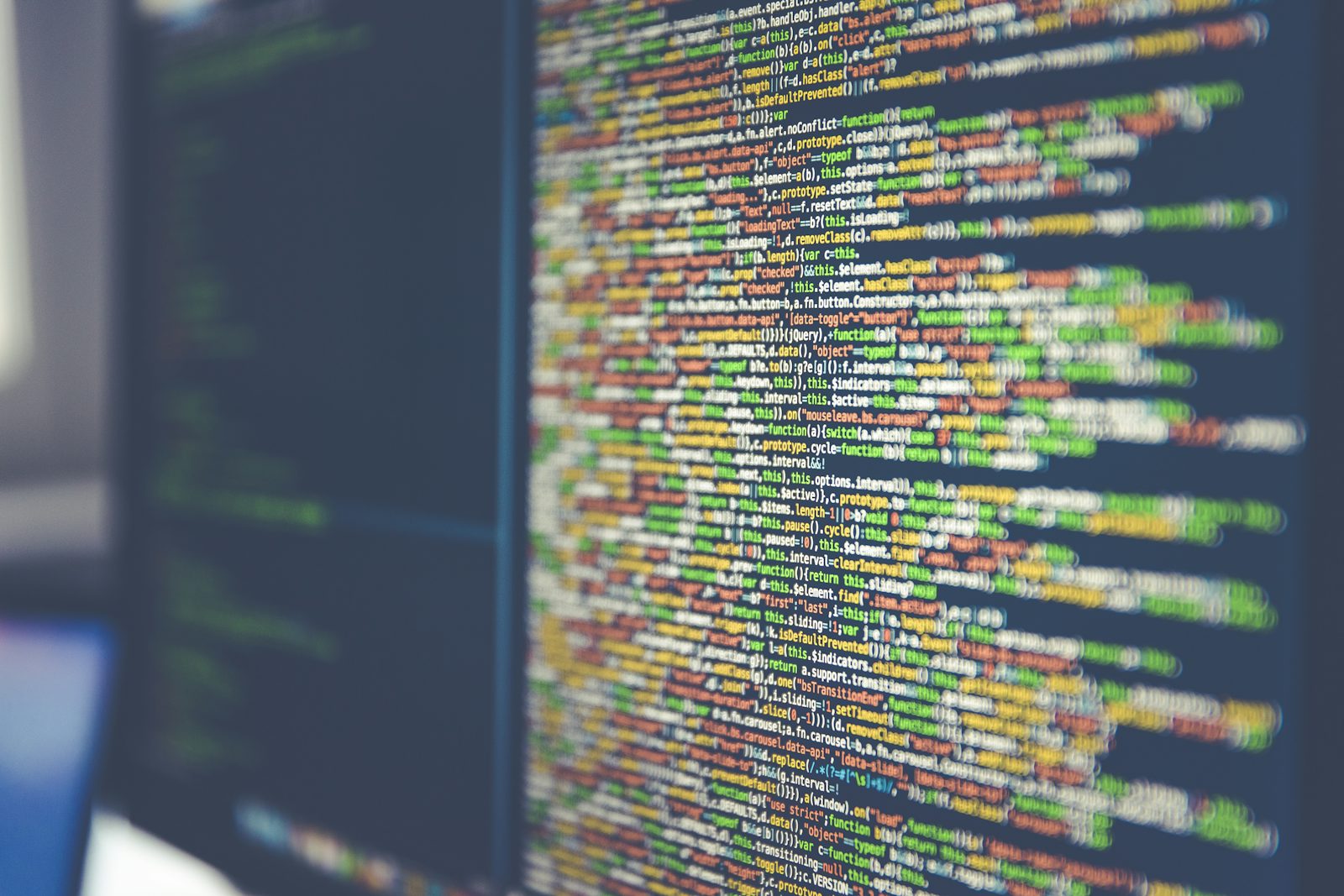 Código colorido em uma tela de computador desfocada.