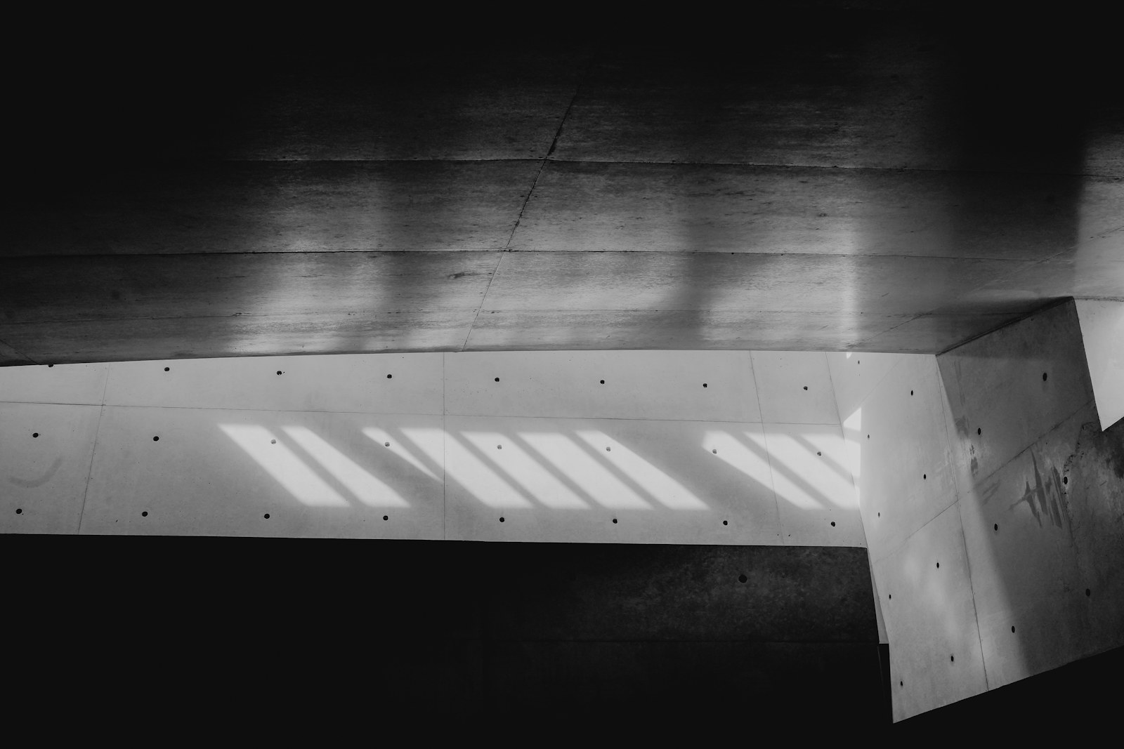 Luz atravessando estruturas geométricas de concreto.